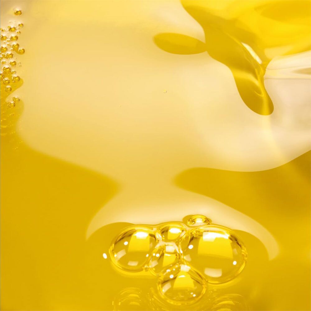 Gros plan sur de l'huile jaune. Quelques bulles sont visibles. Surface liquide.