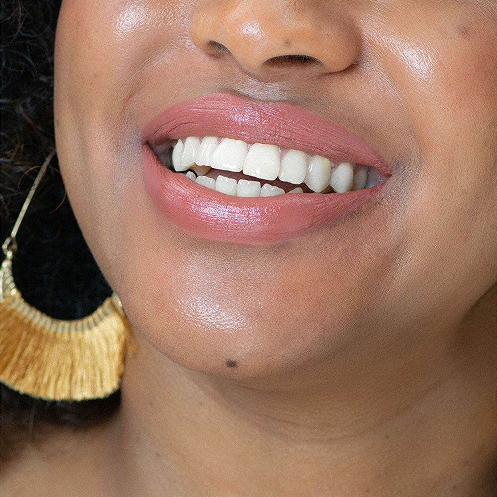 Close-up van lippen met roze lipstick. Gouden oorbellen. Huid met glans.