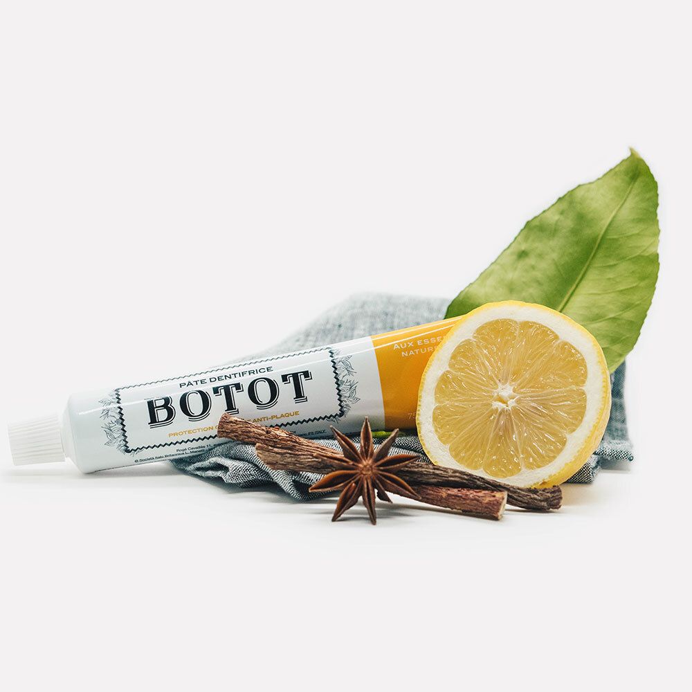 Tube de dentifrice, citron, épices et feuille sur tissu bleu. Inscription BOTOT sur le tube.