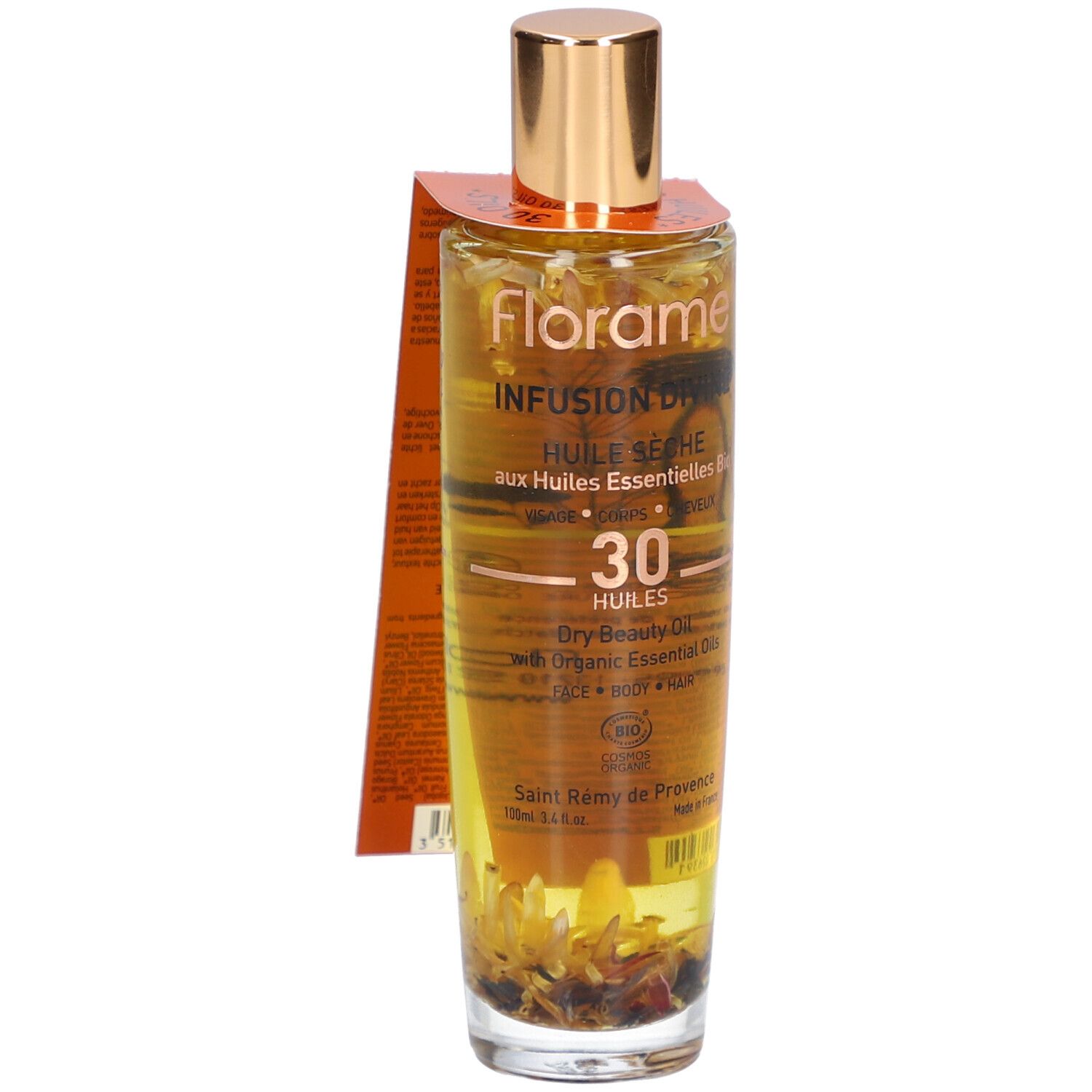 Glazen fles met gouden dop en etiket. Bevat een vloeistof met bloemen. Opschrift: Infusion Divine, Huile Seche.