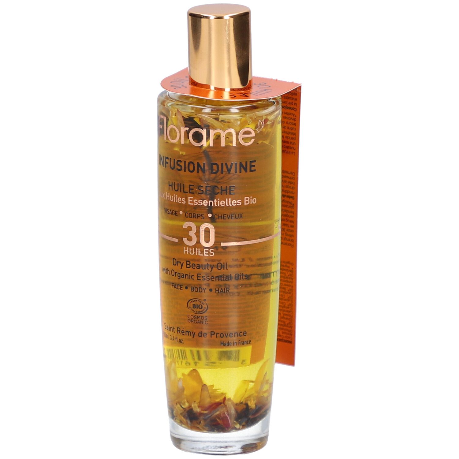 Glazen fles met gouden dop en etiket. Bevat een vloeistof met bloemen. Opschrift: Infusion Divine, Huile Seche.