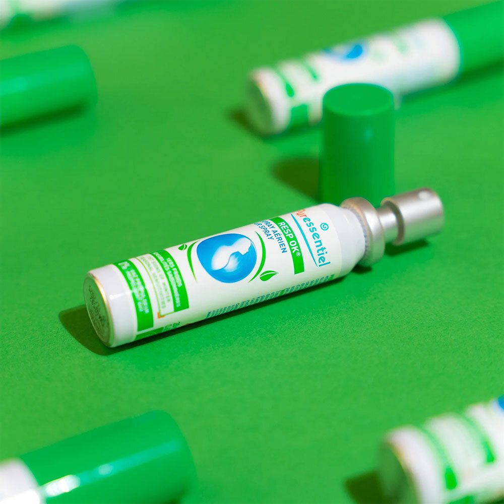 Plusieurs flacons de spray Resp'OK® PURESSENTIEL. Vert et blanc, bouchon vert, sur fond vert.