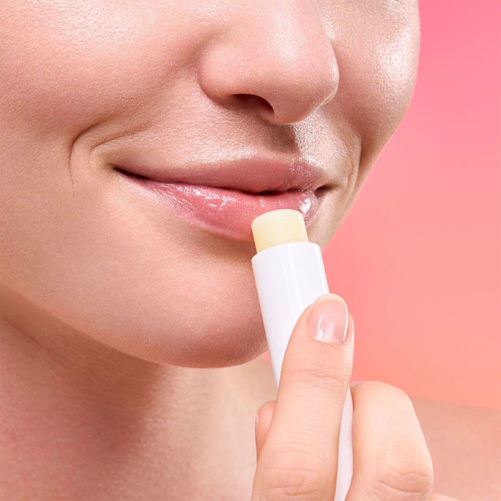 Persoon brengt lippenbalsem aan. Witte stift, gele punt. Glanzende lippen.