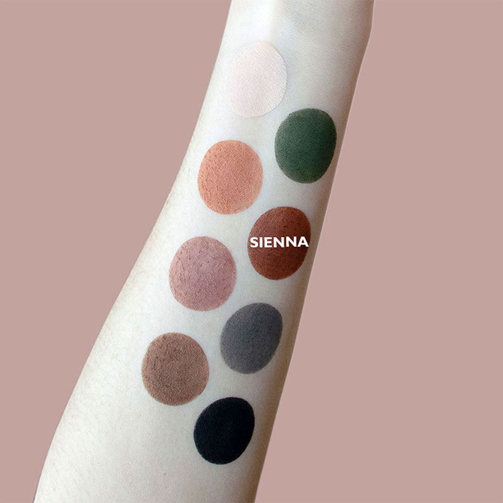 Arm met verschillende ronde oogschaduwkleuren. Kleuren: licht, oranje, groen, bruin, roze, grijs, zwart. Tekst: SIENNA.