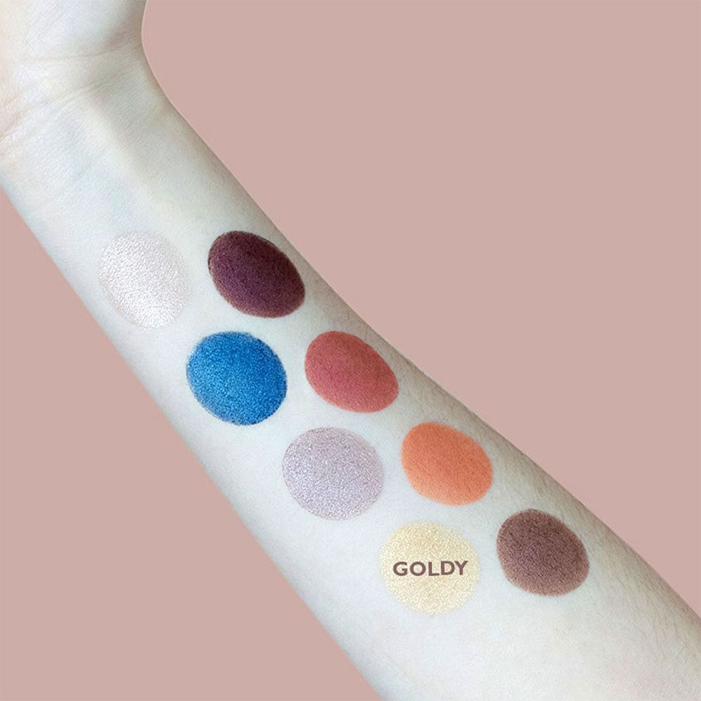 Arm met kleurstalen van oogschaduw. Goldy-tint gemarkeerd. Verschillende tinten in cirkels.