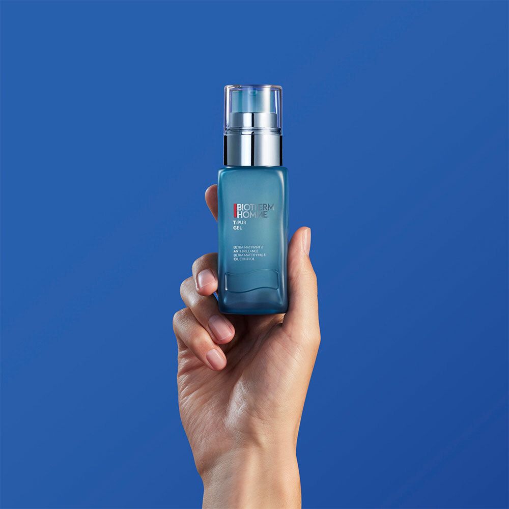 Hand houdt een blauwe fles met zilveren pomp. Opschrift: BIOTHERM HOMME T-PUR GEL.