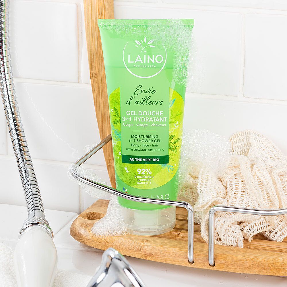 Groene tube met LAINO-logo in een doucheomgeving. Naast de tube een spons en zeepschuim.