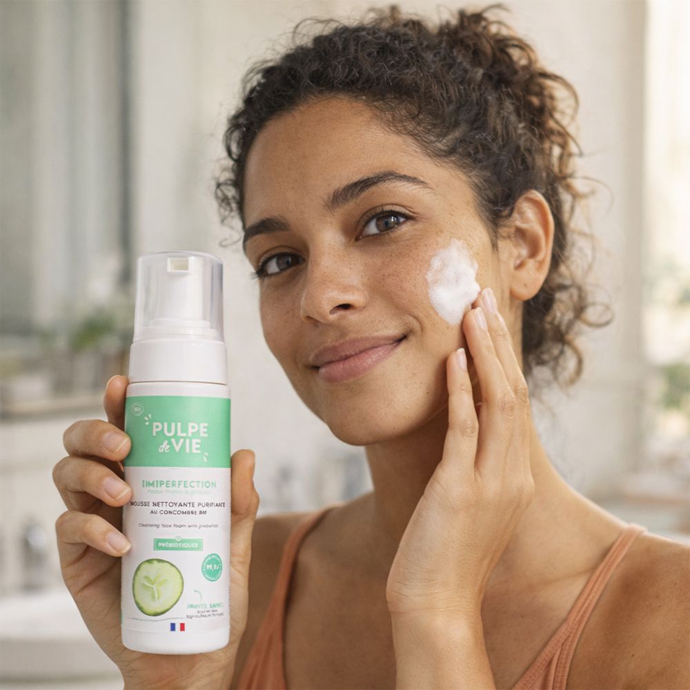 Femme tenant un flacon et appliquant de la mousse sur son visage. Nom du produit et logo visibles. Drapeau français.