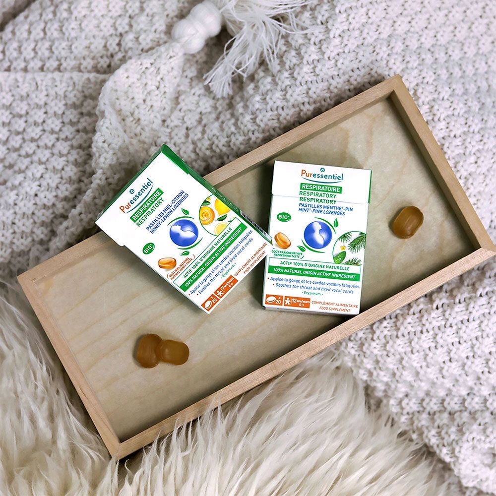 Twee verpakkingen met pastilles op een houten dienblad. Gele pastilles ernaast. Opschrift: RESPIRATOIRE.