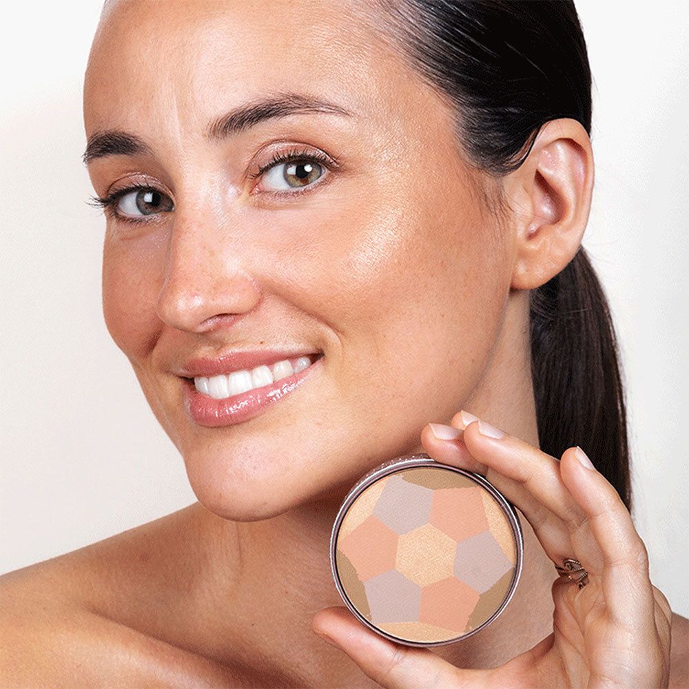 Vrouw houdt ronde cosmeticaverpakking vast. Gezicht met make-up. Verpakking met zeshoekige tinten.