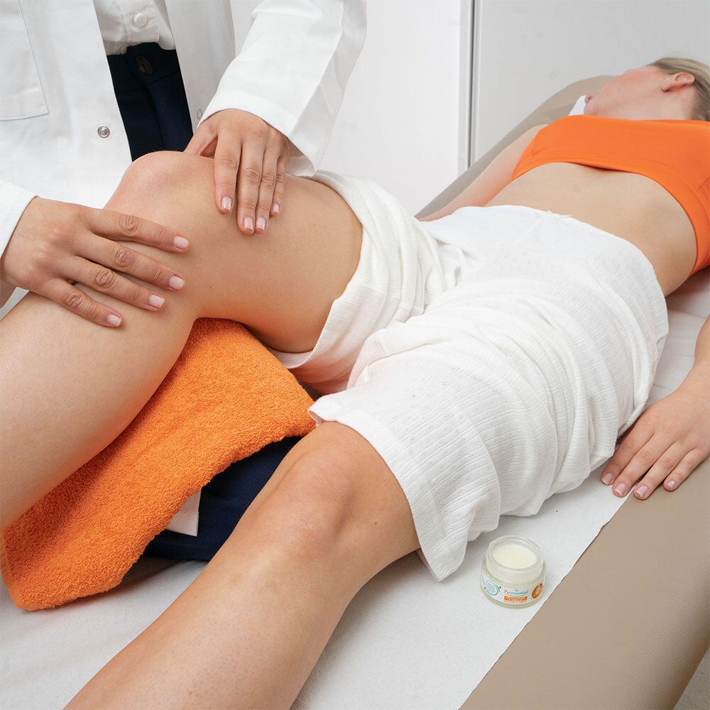 Personen behandelen knie. Opschrift: Puressentiel, Spieren & Gewrichten, verzachtende balsem. 14 essentiële oliën.