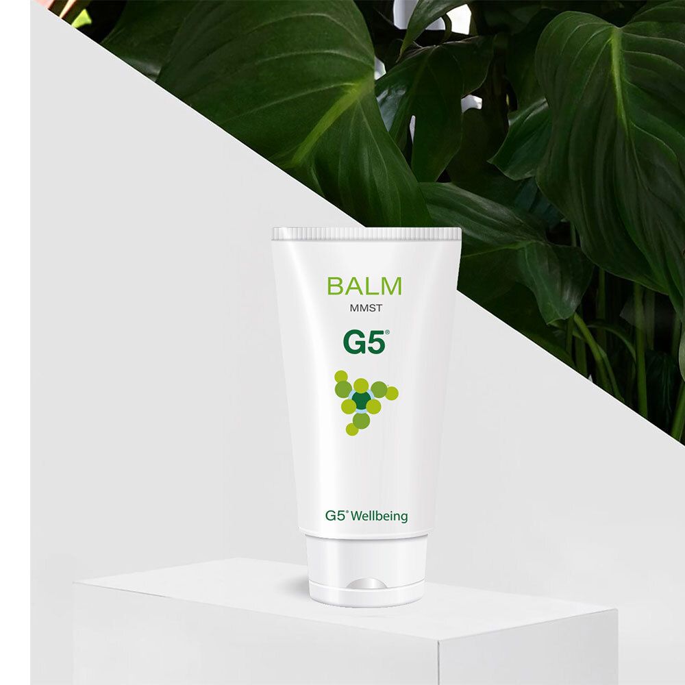 Tube blanc avec texte vert. Le tube porte "BALM MMST G5". Le tube est sur une plateforme blanche devant du vert.
