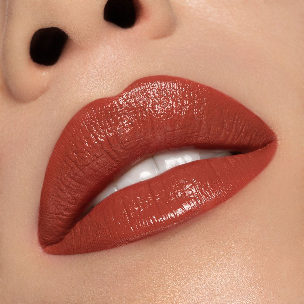 Close-up van lippen bedekt met semi-matte perzikroze lipstick. Huidtint zichtbaar. Glanzende finish.