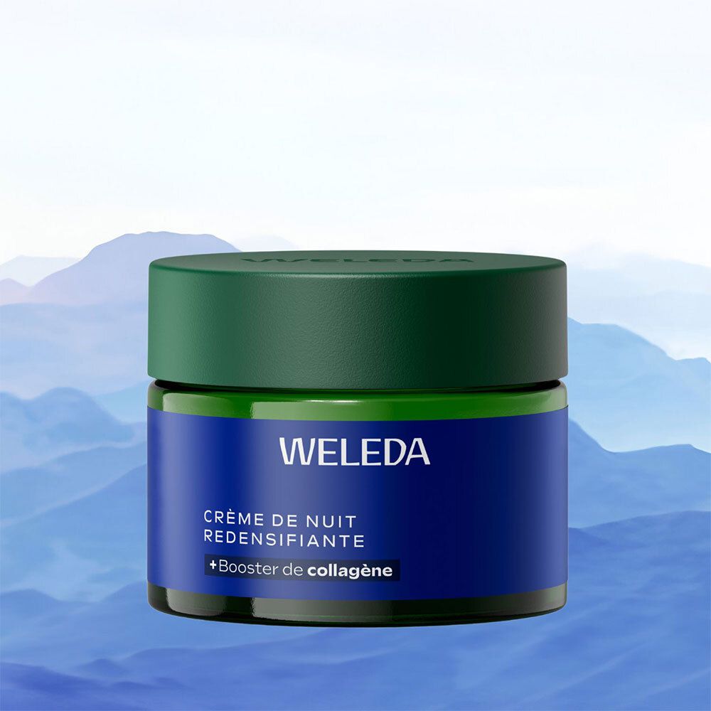 Donkerblauwe crème pot met groene deksel. Opschrift WELEDA en Crème de Nuit Redensifiante. Achtergrond: bergen.