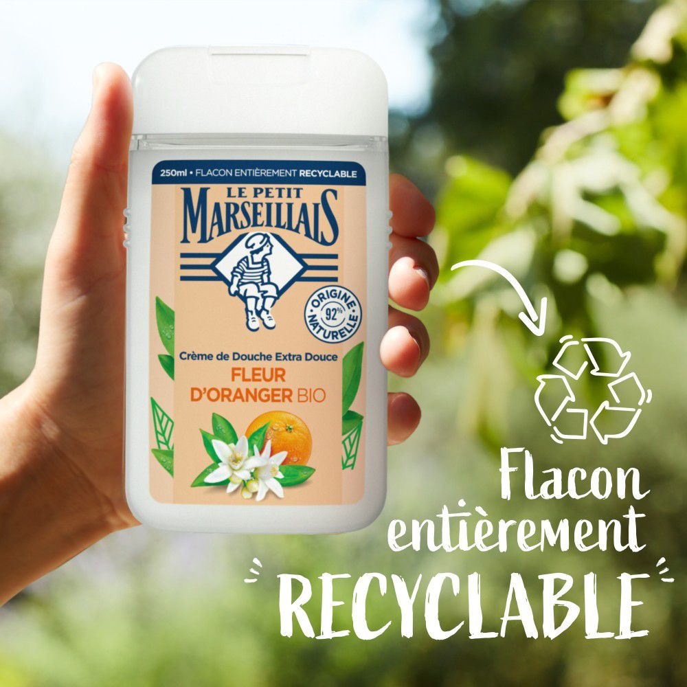 Main tenant un flacon de crème de douche. Texte: Flacon entièrement recyclable. Symbole de recyclage.