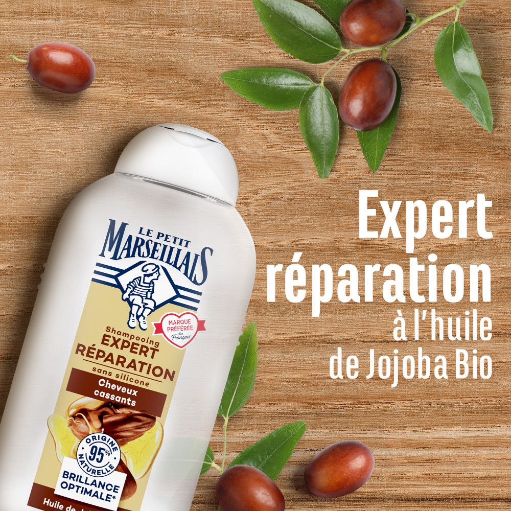 Flacon de shampooing et fruits sur bois. Texte: Expert Réparation à l'huile de Jojoba Bio. Le Petit Marseillais.