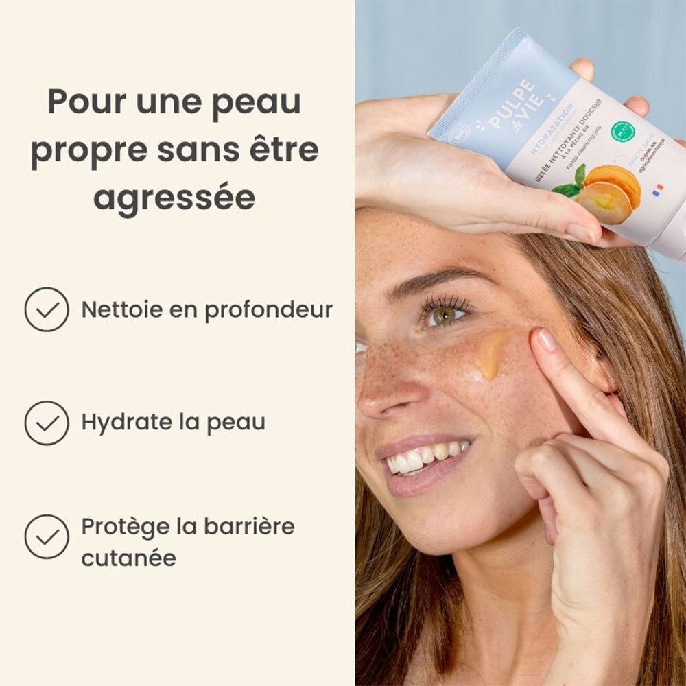 Persoon toont lichtblauwe tube gezichtsreinigingsgel. Tekst: 'Nettoie en profondeur', 'Hydrate la peau', 'Protège'.