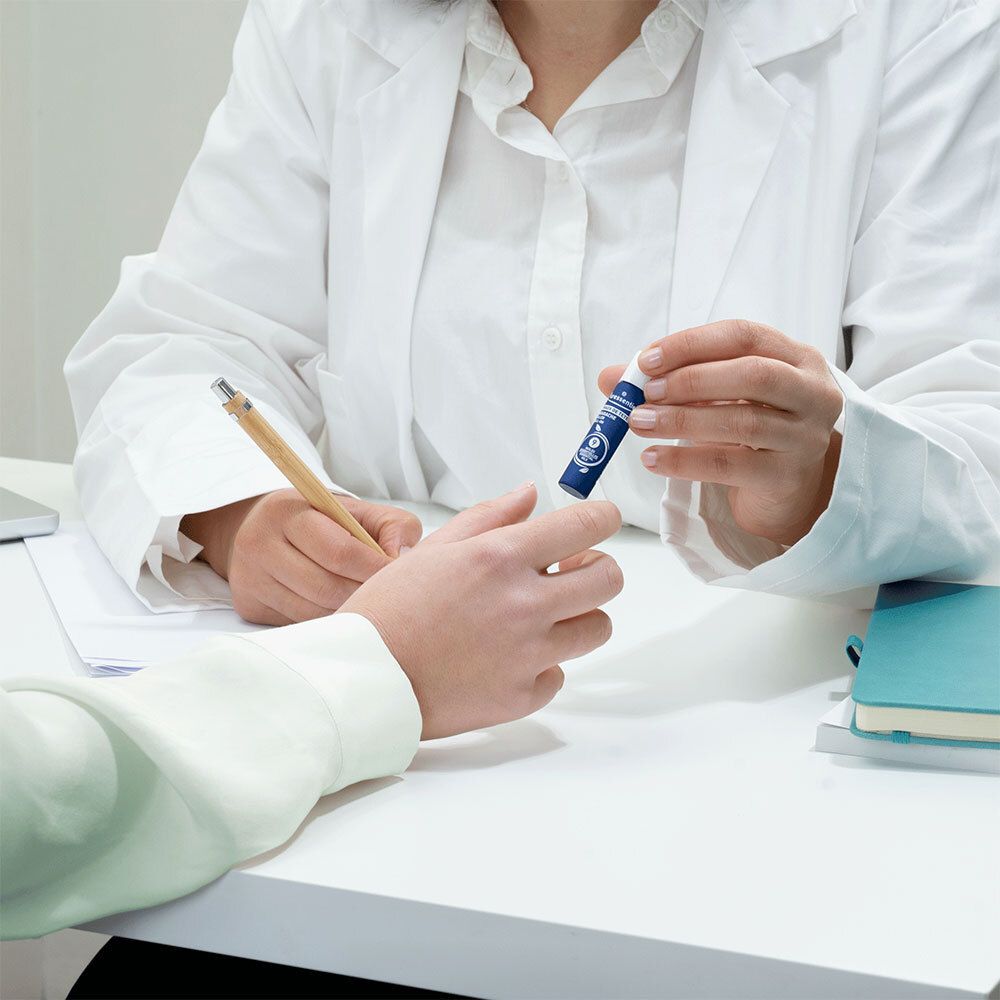 Persoon geeft product aan ander. Product: roll-on. Merk: Puressentiel. Blauw etiket.