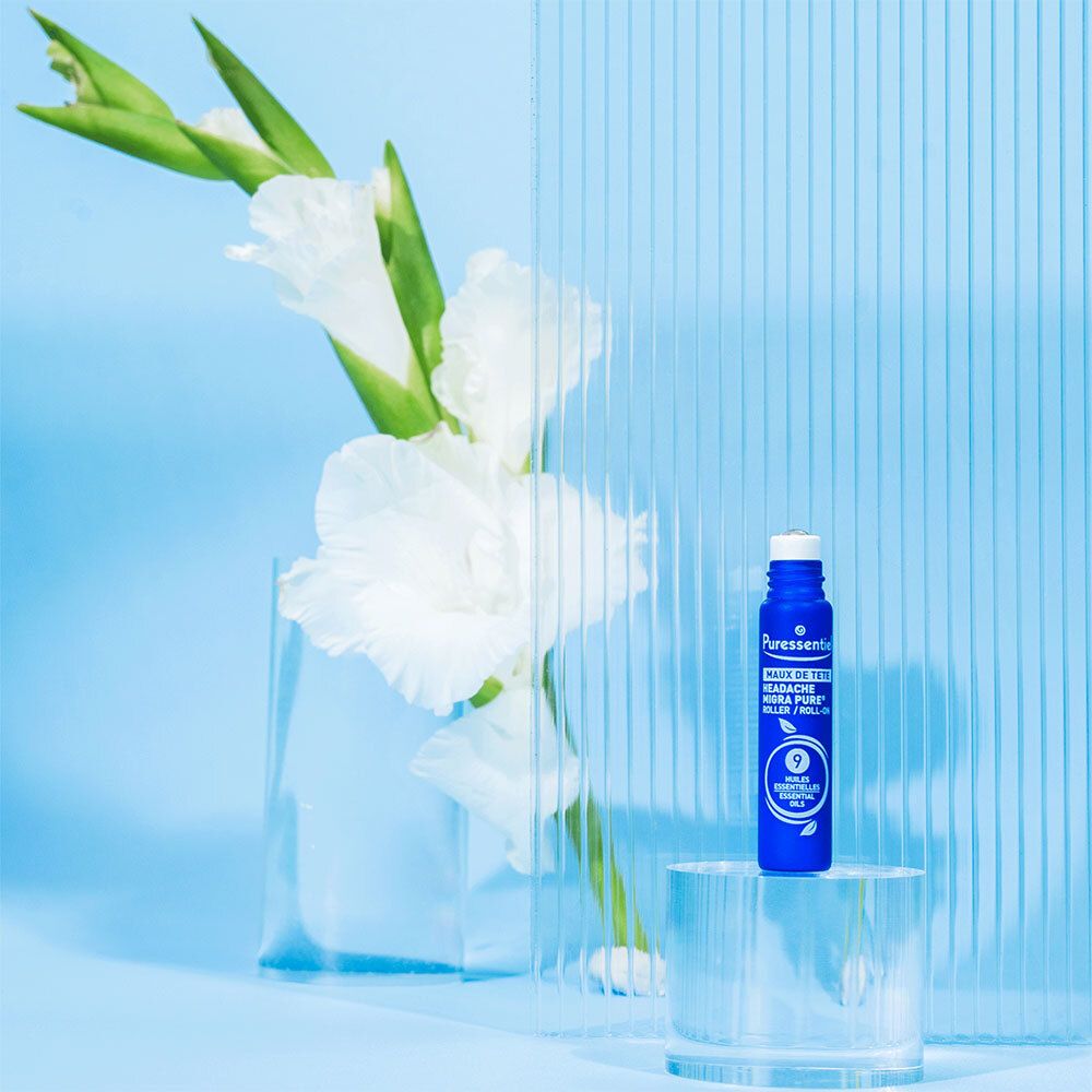Blauwe roll-on. Merk: Puressentiel. Tekst: Maux de tête. Op glazen plaat voor bloemen.