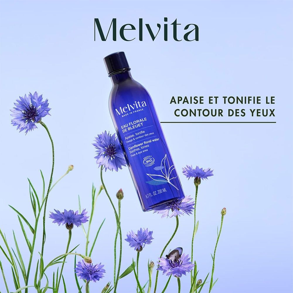 Flacon Melvita Eau Florale de Bleuet entouré de bleuets. Texte: Apaise et tonifie le contour des yeux.