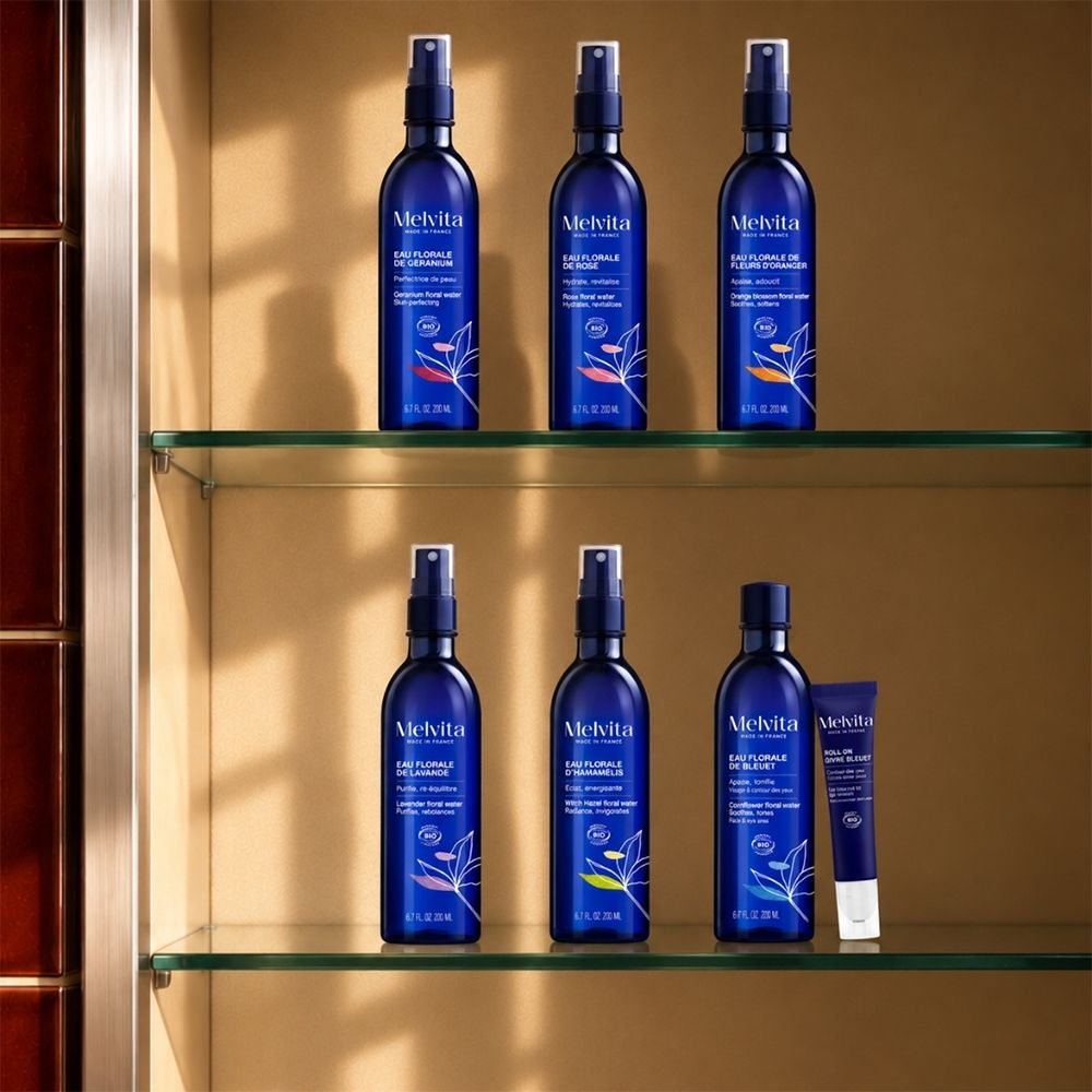 Meerdere blauwe Melvita sprayflessen en een kleine tube in een schap.