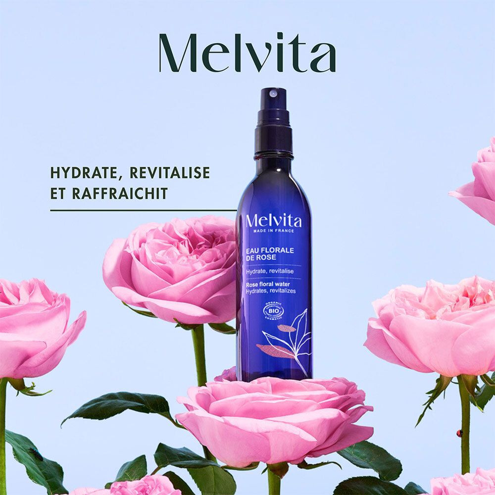 Melvita rozenbloesemwaterfles omringd door roze rozenbloesems.