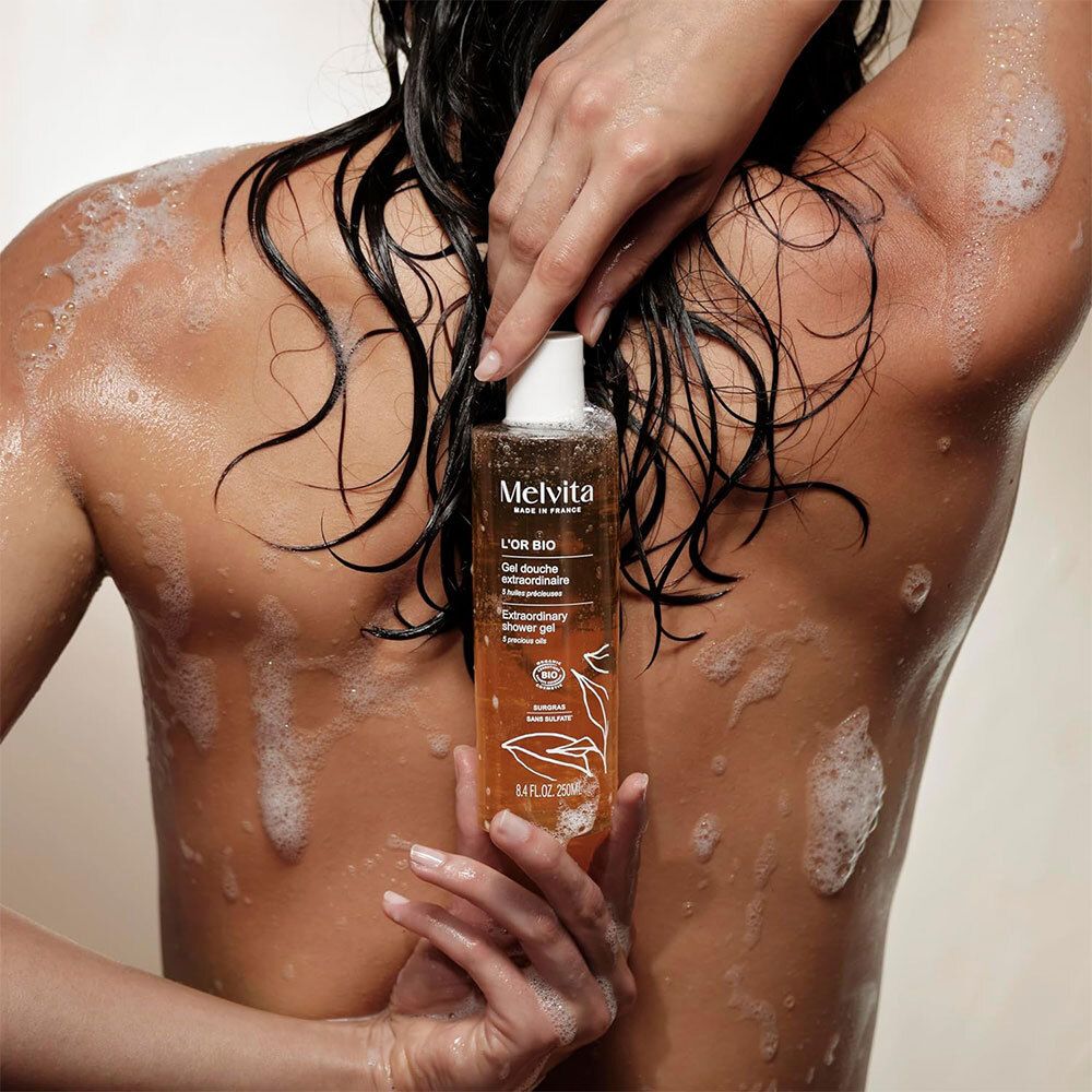 Persoon met Gel Douche Extraordinaire. Fles met tekst: L'Or Bio, Gel Douche Extraordinaire.