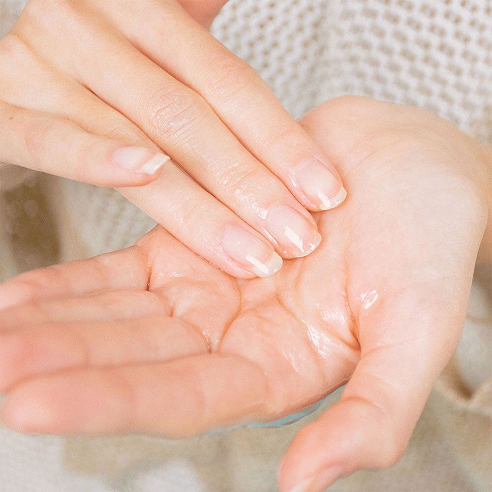 Mains avec de l'huile. Les paumes sont recouvertes d'huile. Peau claire, ongles courts. Gros plan.