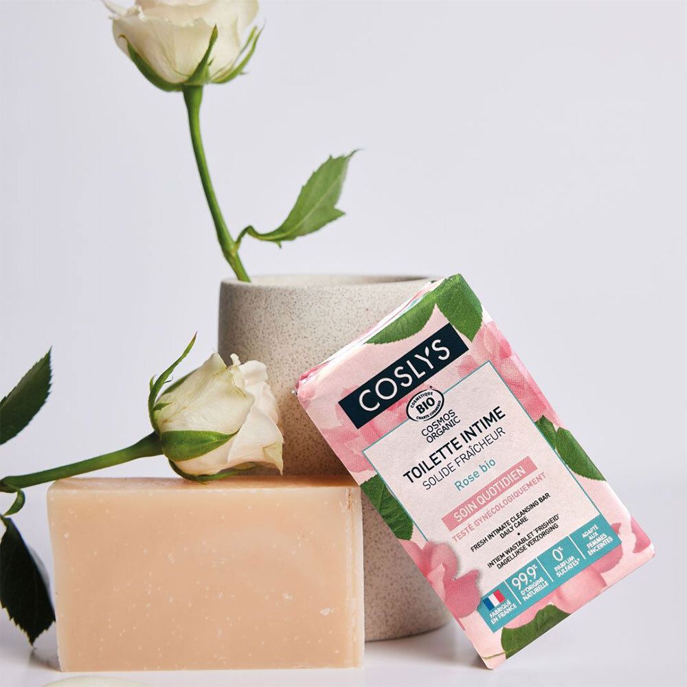 Savon rose et emballage à côté d'un vase avec rose. Savon avec nom du produit: Coslys Solide fraîcheur Toilette intime.