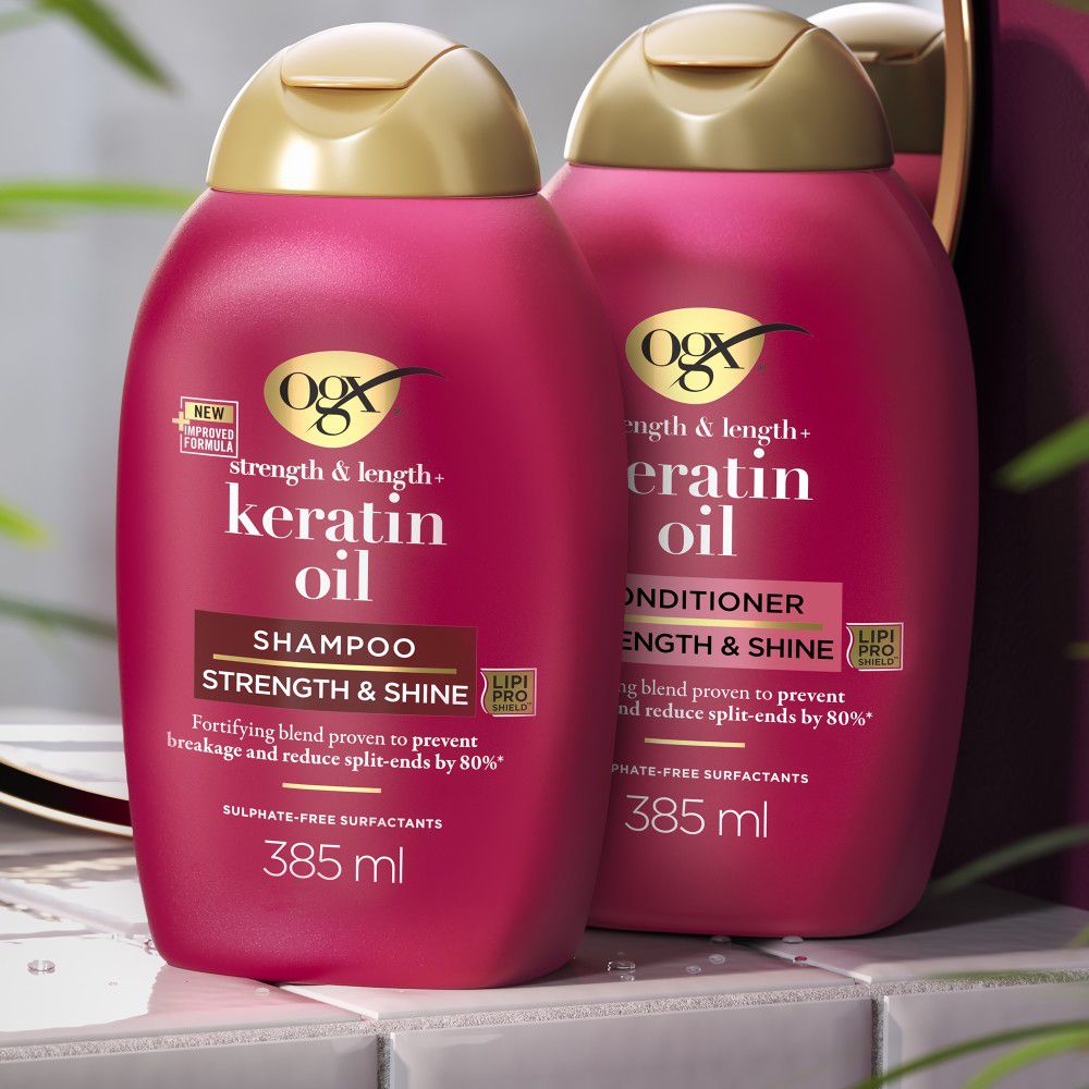 Deux flacons de shampooing rouges avec bouchons dorés. Texte : OGX, Keratin Oil, Shampooing, 385 ml.