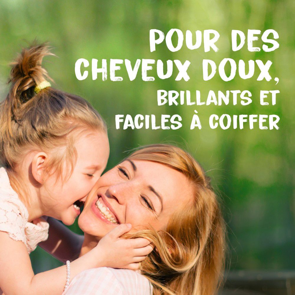 Moeder en kind omarmen elkaar. Tekst: Pour des cheveux doux, brillants et faciles à coiffer.