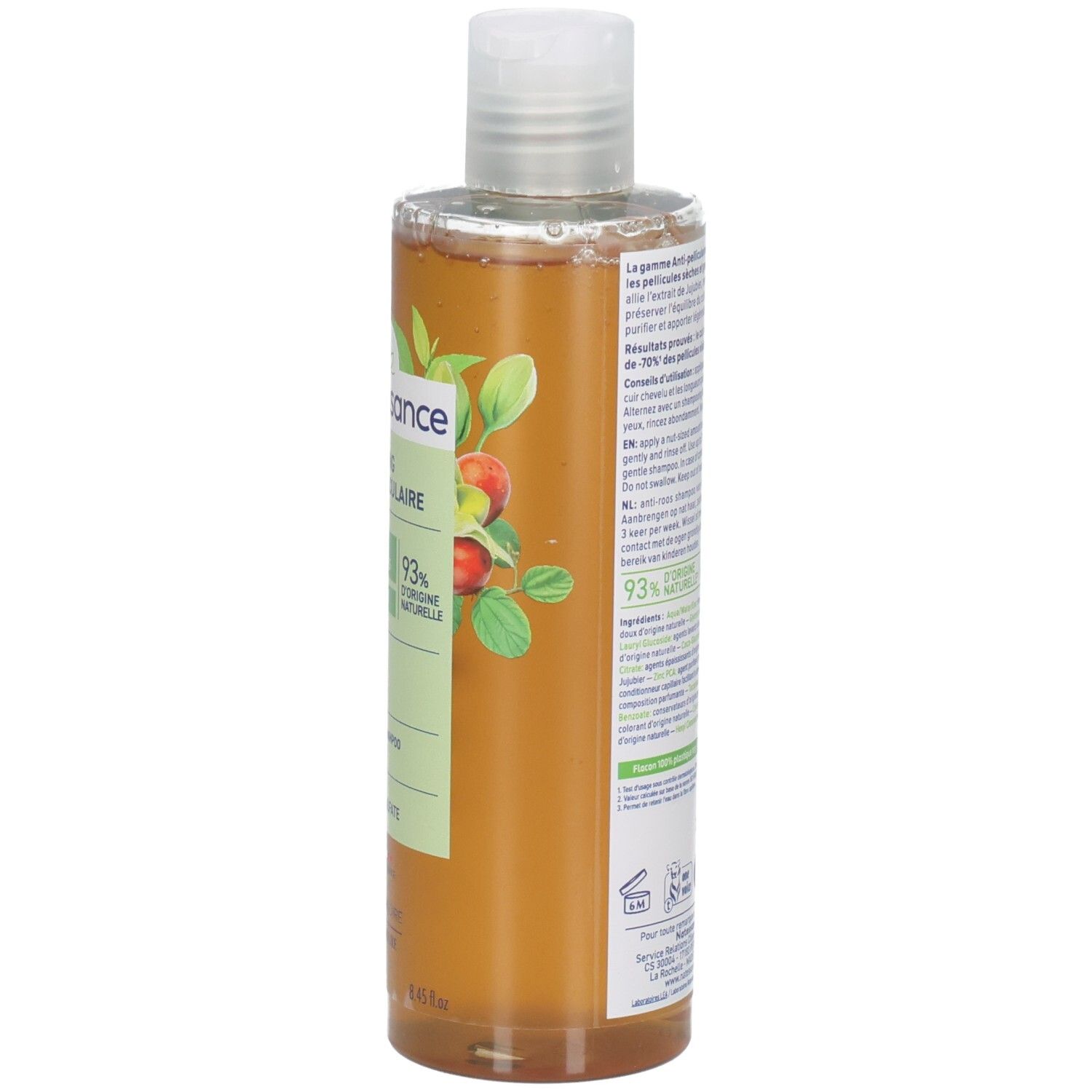 Vue en biais du flacon de shampooing. Étiquette avec nom du produit, ingrédients et logo. Liquide ambré.
