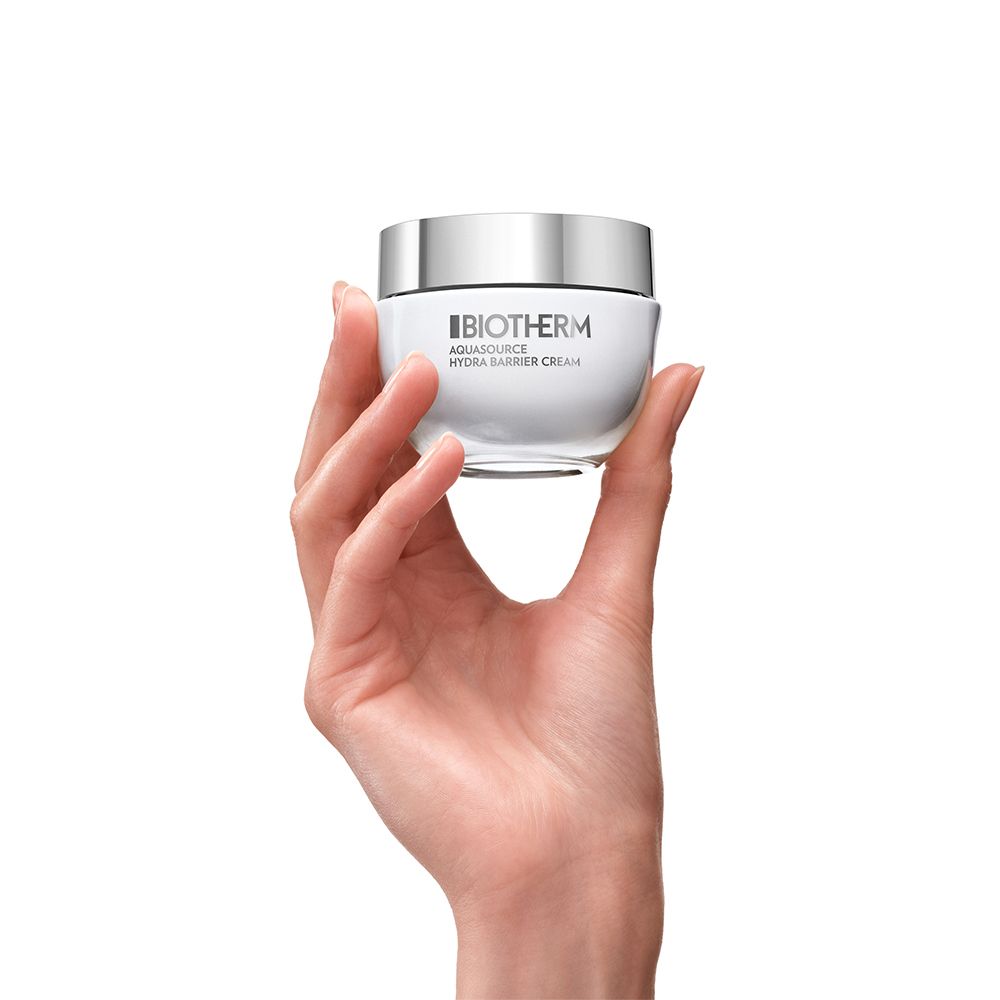 Main tenant un pot blanc de crème barrière hydratante Biotherm Aquasource.