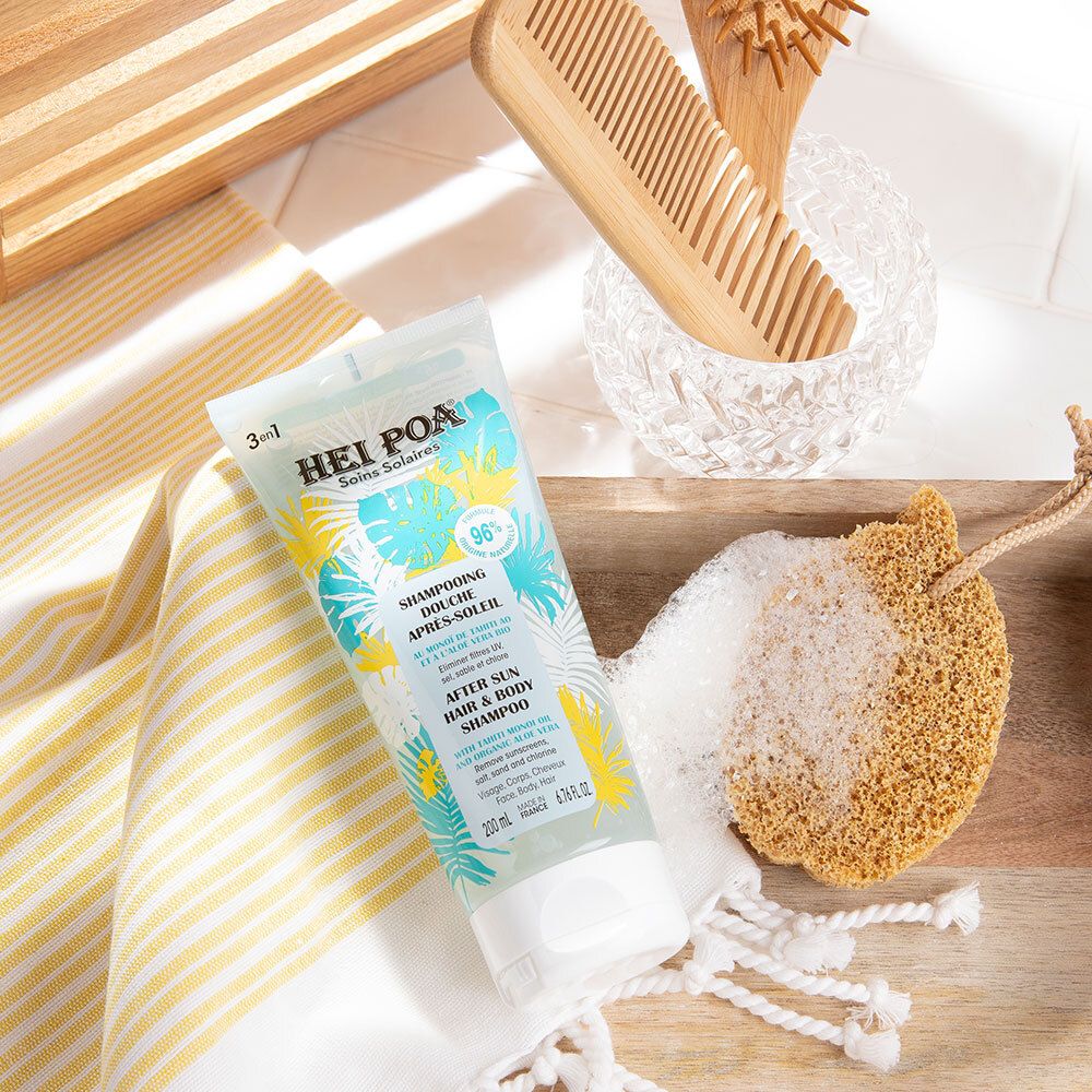 Produit sur une serviette jaune et blanche et une planche en bois. À côté : éponge, peigne et récipient en verre. Produit : tube avec impression HEI POA.