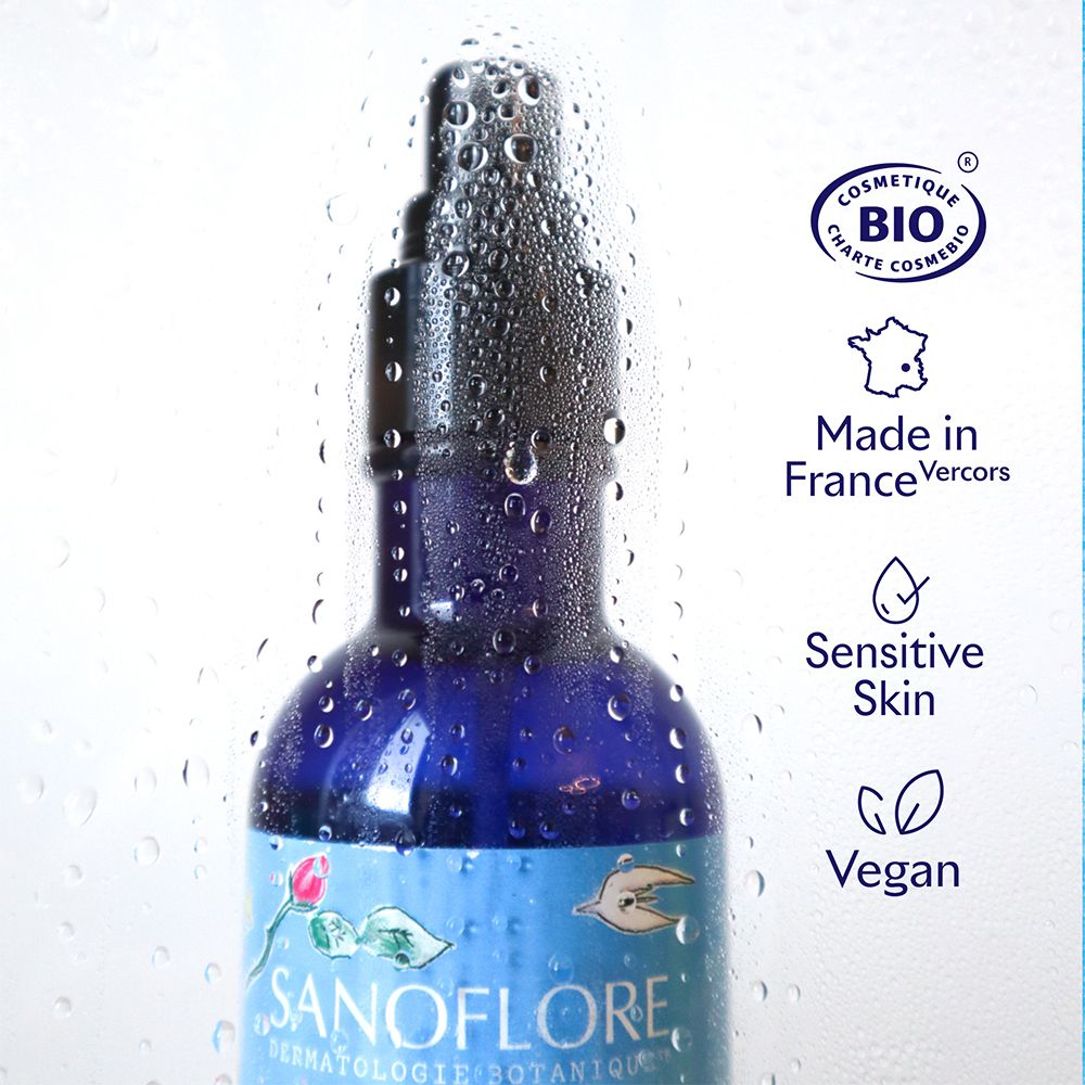 Flacon bleu avec vaporisateur, couvert de gouttes d'eau. Certification Bio, Vegan, Sensitive Skin.