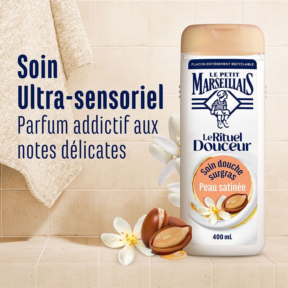 Productfles naast handdoek en bloemen. Tekst: Soin Ultra-sensoriel Parfum addictif aux notes délicates.