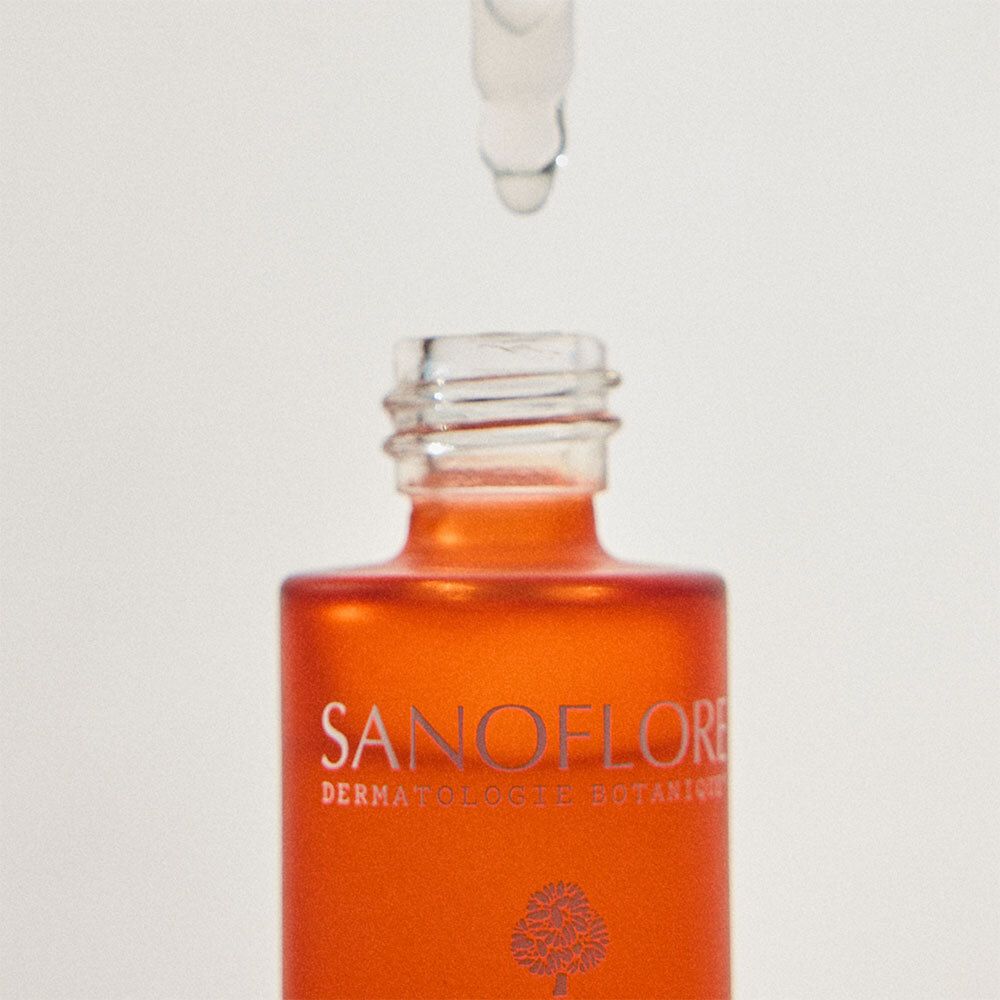 Close-up van de flessenhals van Sanoflore Anti-aging Serum. Druppel valt uit de pipet.