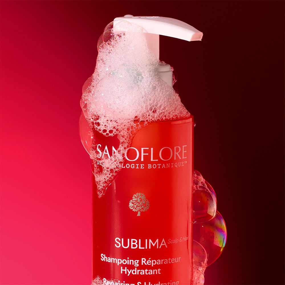 Flacon de shampooing SANOFLORE Sublima avec mousse. Fond rouge.