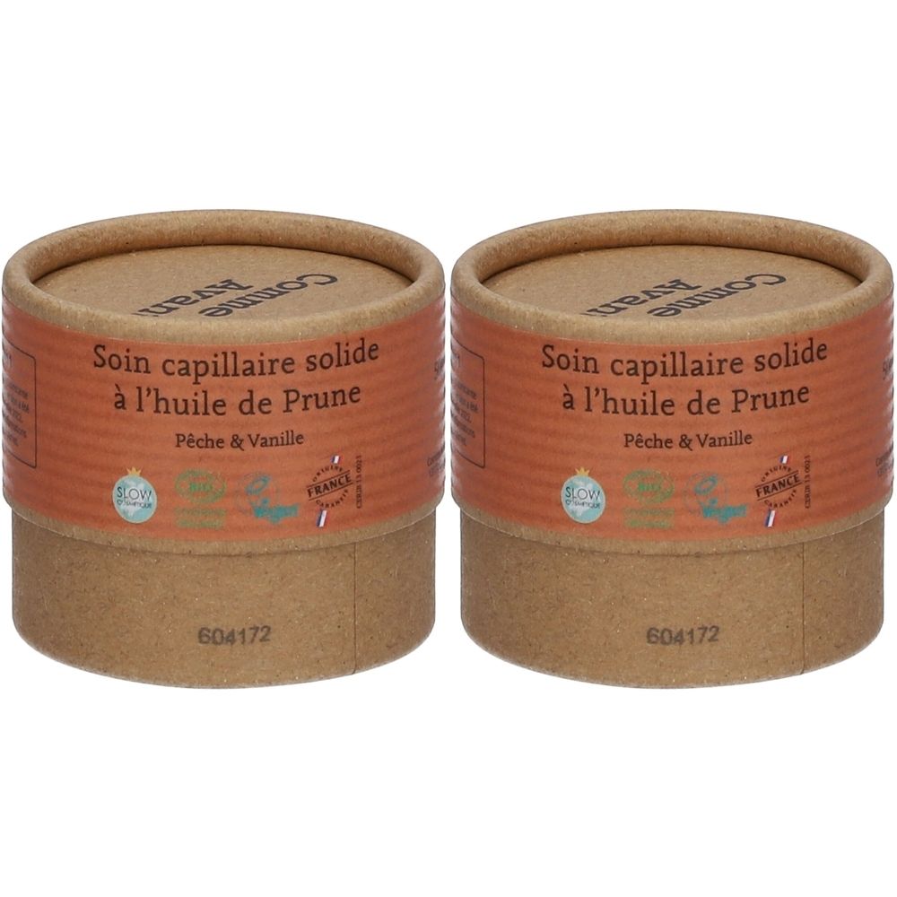Twee cilindrische dozen van bruin karton. Opschrift: Soin capillaire solide à l'huile de Prune, Pêche & Vanille. Met certificeringen.