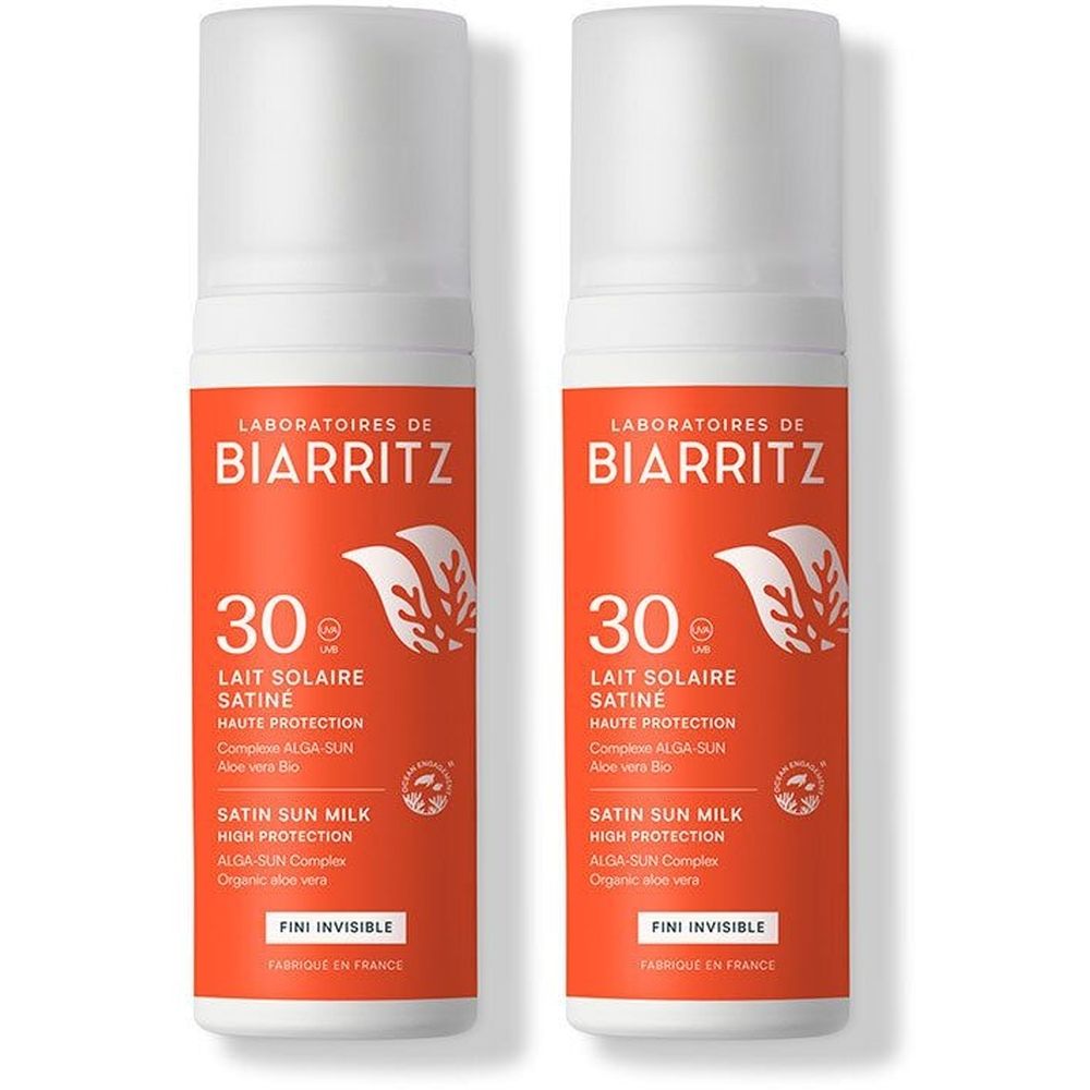 Deux flacons de lait solaire avec bouchon blanc et étiquette orange. On lit "Laboratoires de Biarritz", "30", "Lait Solaire Satiné", et "Fini Invisible".
