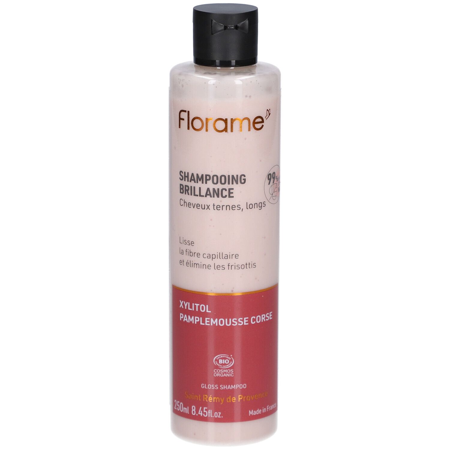 Fles Shampooing Brillance. Transparante, roze vloeistof. Zwarte dop. Rood etiketgedeelte met tekst. FLORAME logo.