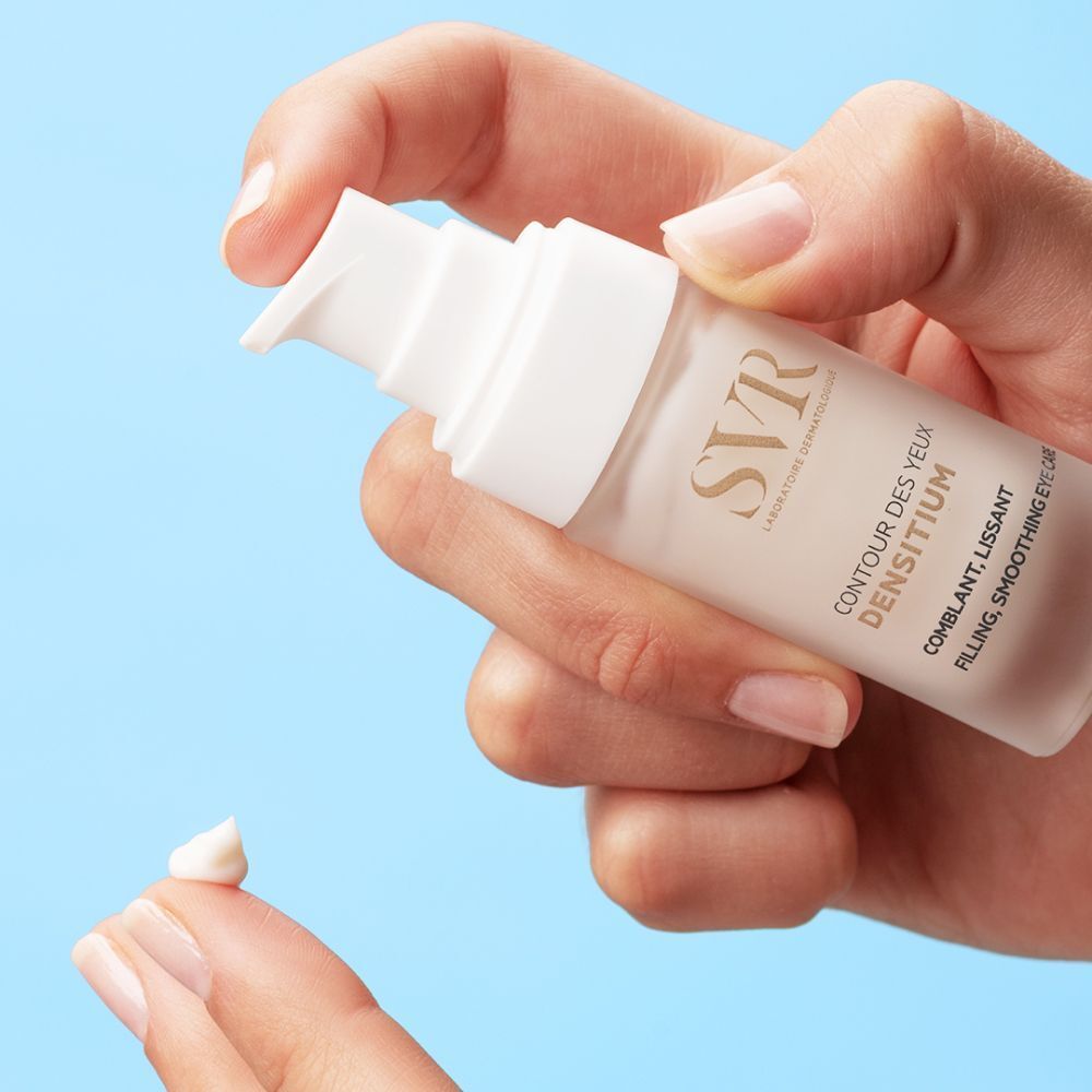 Hand houdt flacon vast. Opschrift: SVR, Densitium Contour des Yeux, Comblant, Lissant, Filling, Smoothing Eye Care. Crème op vinger.