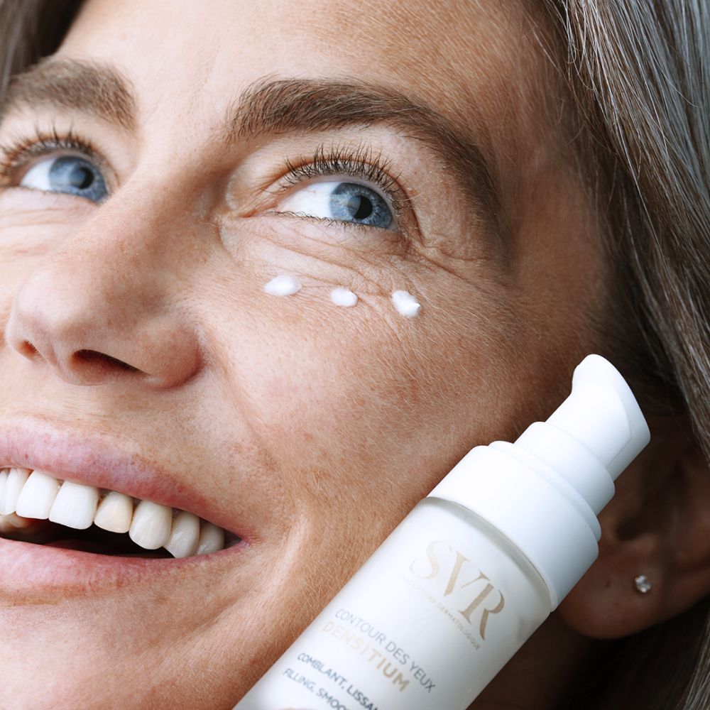 Vrouw houdt flacon vast. Opschrift: SVR, Densitium Contour des Yeux, Comblant, Lissant, Filling, Smoothing Eye Care. Crème onder ogen.