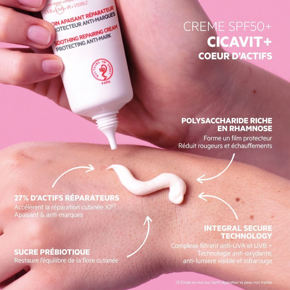 Une main tient un tube de SVR Cicavit+ Crème SPF50. Le fond est bleu. Le tube est blanc avec texte rouge et noir.