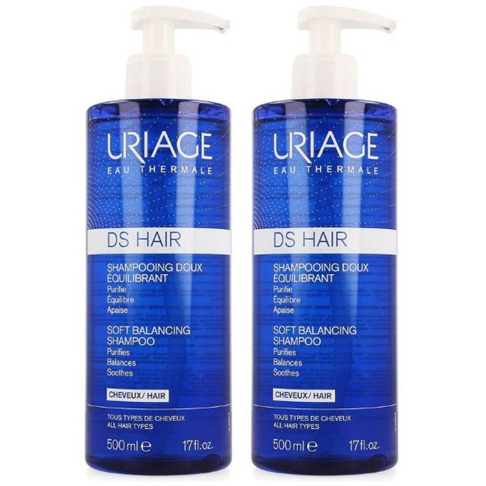 Twee blauwe flessen Uriage DS Hair Shampooing Doux Équilibrant. Witte pompen. Tekst in het Frans en Engels.