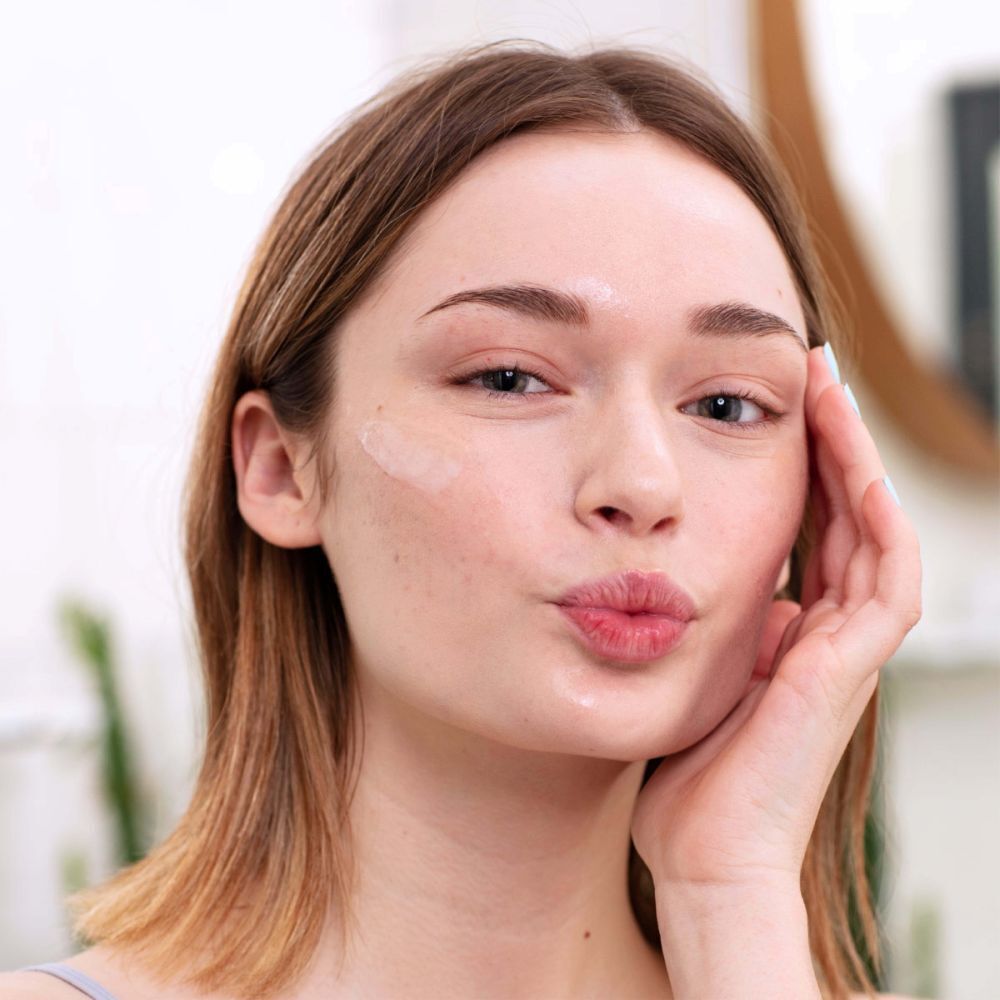 Femme touchant son visage avec un flacon SVR [AZ] Sebiaclear Ampoule Flash. Visage au premier plan.