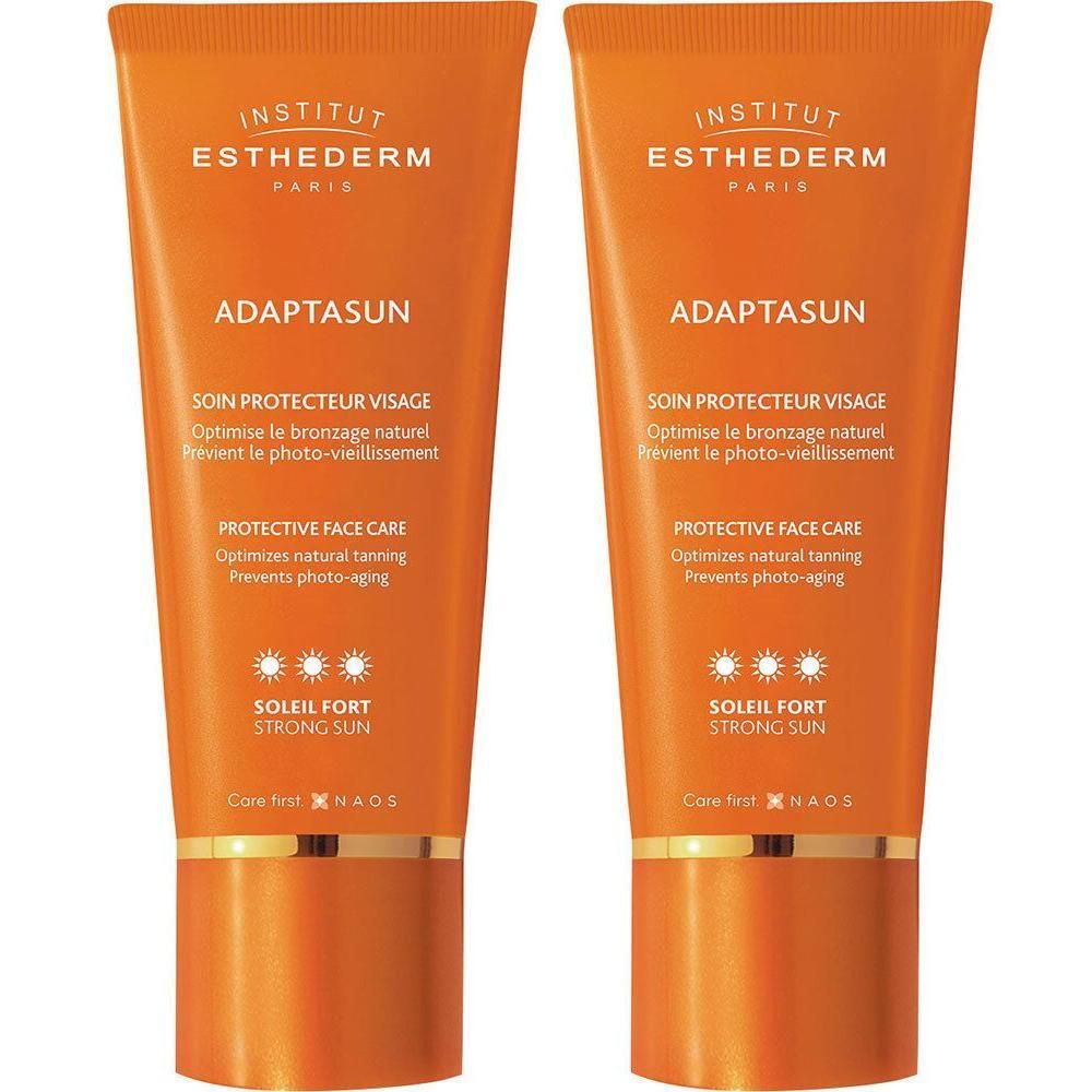 Deux tubes de crème solaire Adaptasun. Emballage orange avec texte blanc. Nom du produit et logo soleil.