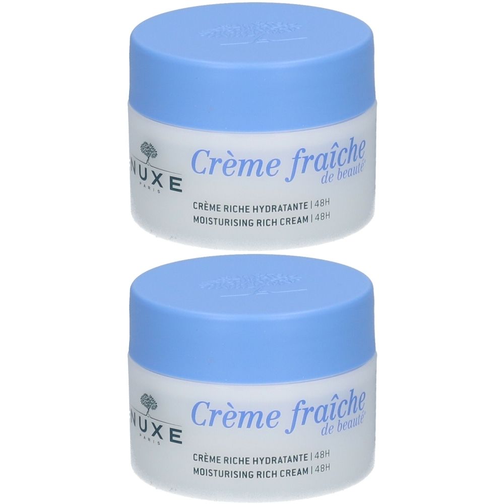 Deux pots de crème Nuxe Crème fraîche de beauté. Pots blancs avec couvercles bleu clair. Inscription : Crème fraîche de beauté, Crème Riche Hydratante 48H.