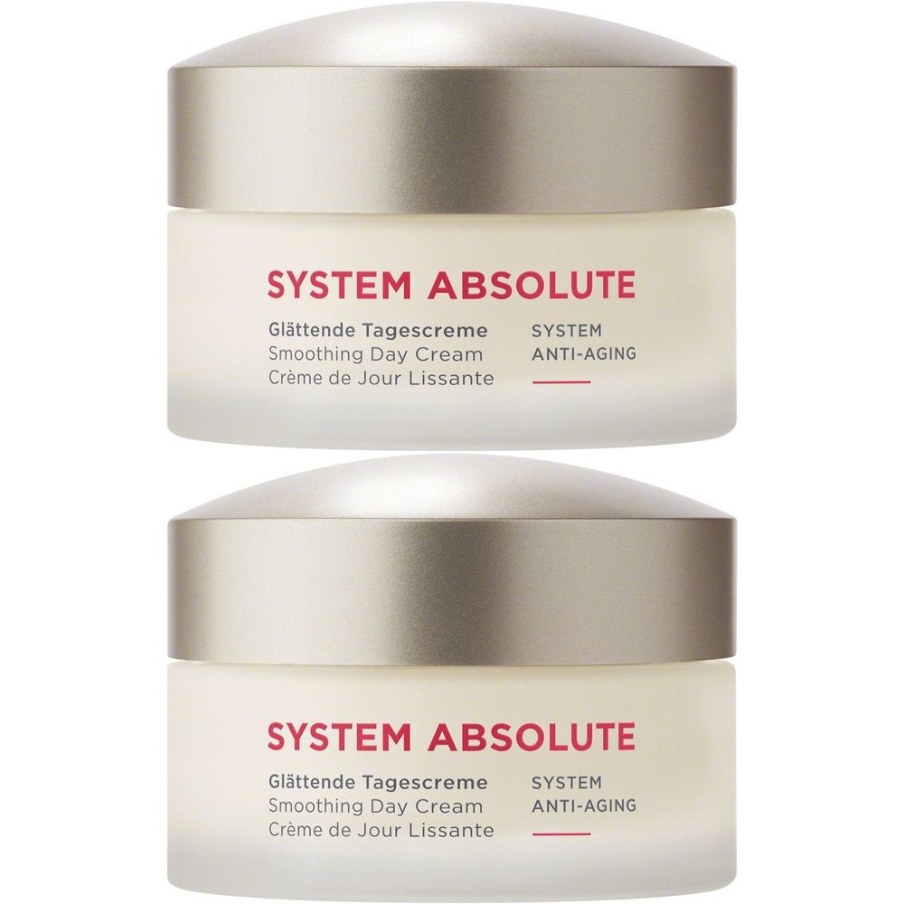 Twee crèmepotten met zilverkleurige deksels. Opschrift: SYSTEM ABSOLUTE, Glättende Tagescreme, Smoothing Day Cream, Crème de Jour Lissante, SYSTEM ANTI-AGING.