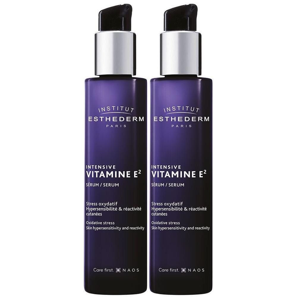 Twee flessen INSTITUT ESTHEDERM Intensiv-Vitamin E2 serum. Paarse flessen met zilveren pompkopjes. Tekst: Intensiv Vitamin E2, Serum.